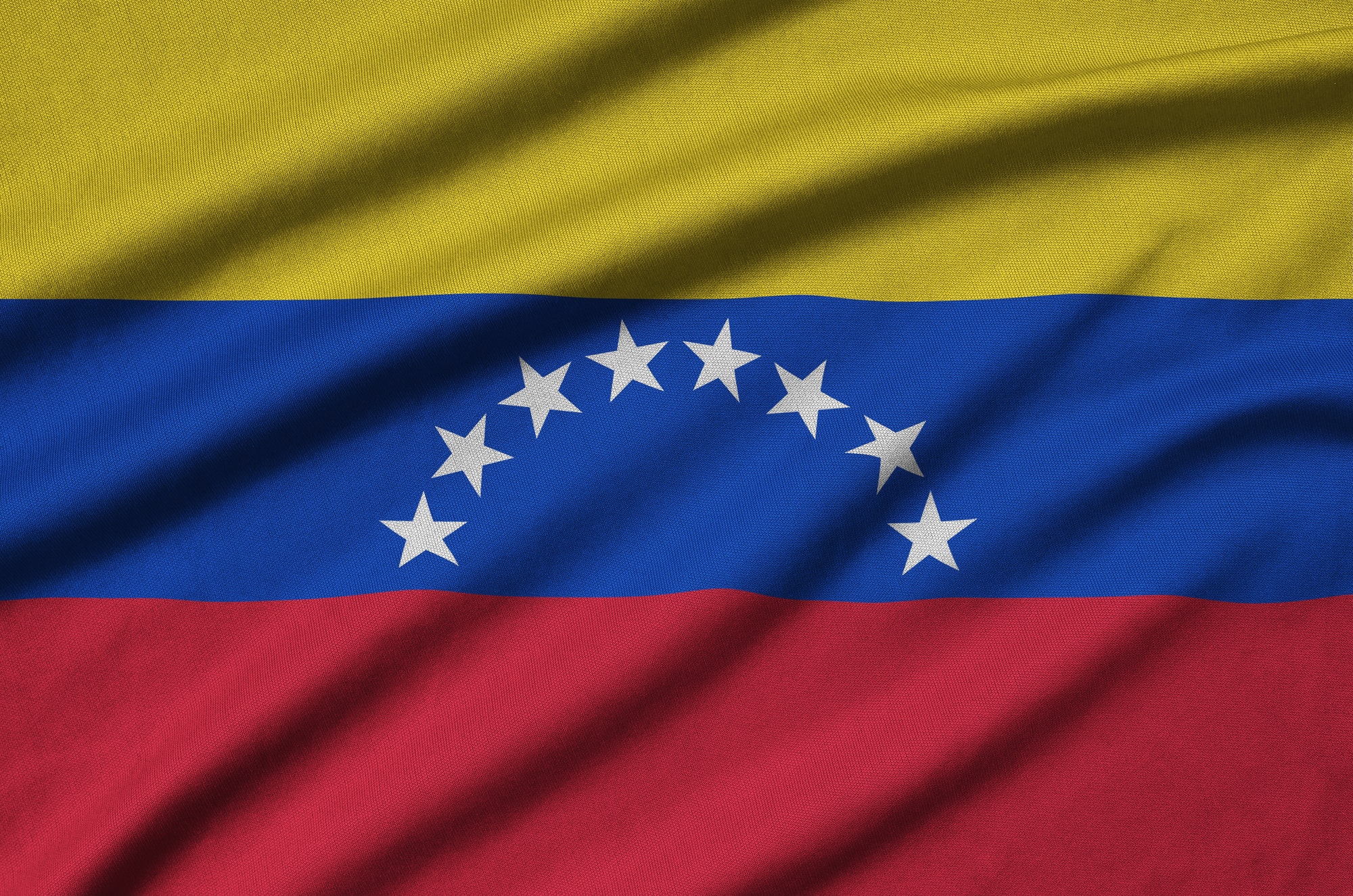 Venezuela flag is depicted on a sports cloth fabric with many folds. Sport team waving banner